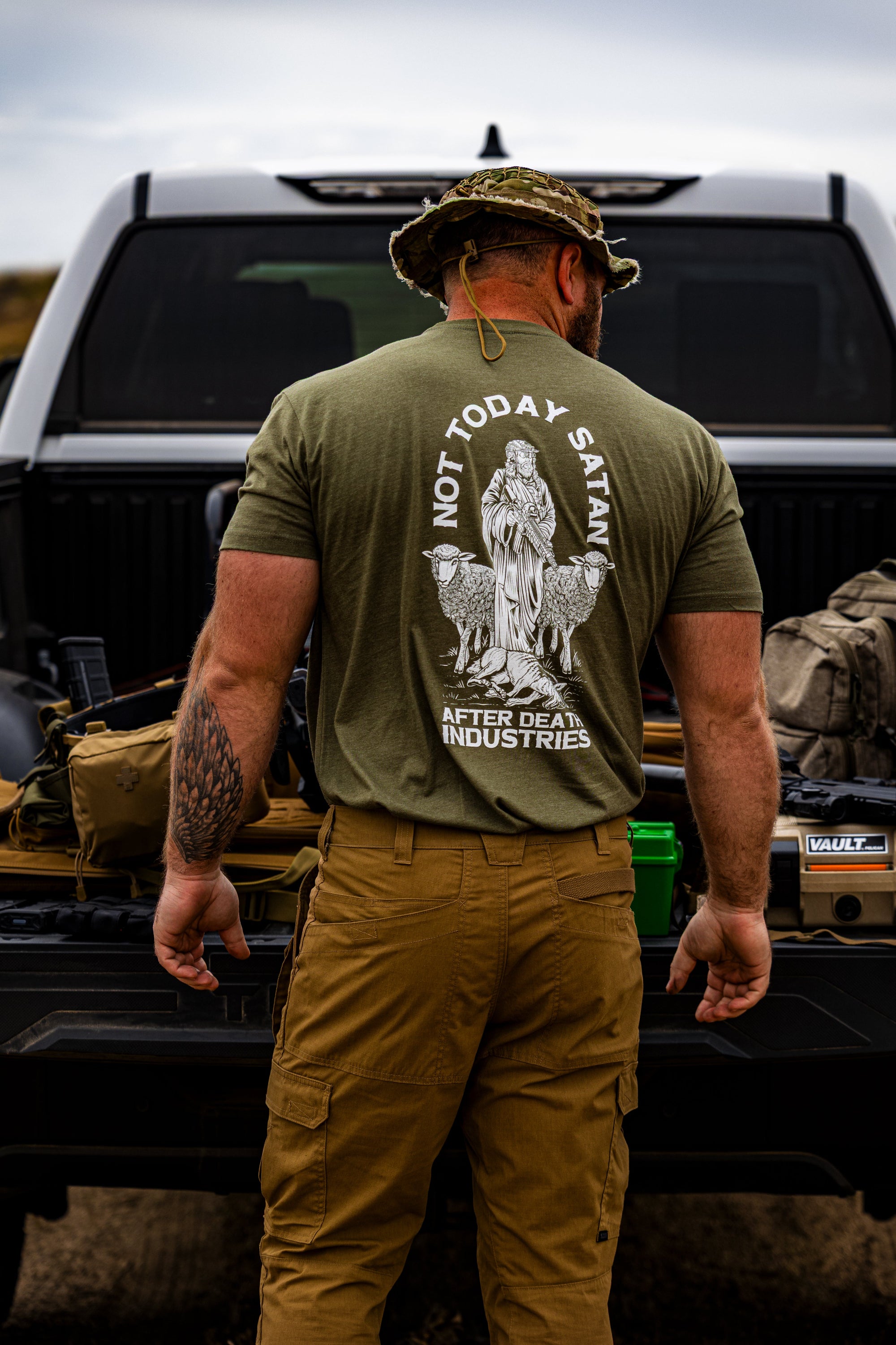 Man wearing a green t-shirt with a graphic design standing next to a truck.