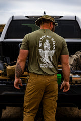 Man wearing a green t-shirt with a graphic design standing next to a truck.